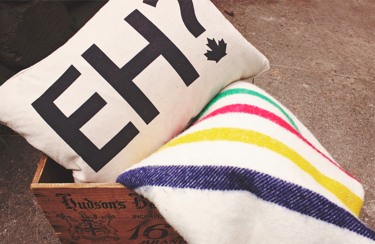 Canada Day Essentials. "Eh" pillow, Hudson's Bay pointe blanket, Hudson's Bay vintage crate | Alex Inspired